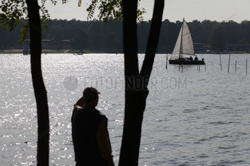 Berlin  Deutschland  ein Mann schaut zu einem Segelboot auf dem Langen See