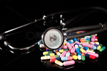 Berlin  Deutschland  Stethoskop und bunte Pillen auf einem schwarzen Hintergrund