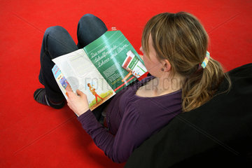 Eine Frau liest in einer Zeitschrift  Kinderland Rostock