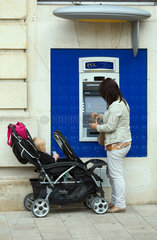 Reims  Frankreich  Frau mit Kleinkind an einem Geldautomaten der Banque et Assurance LCL
