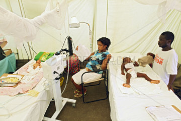 Carrefour  Haiti  Mann und Frau sitzen im Intensivzelt und faecheln ihren Kindern Luft zu