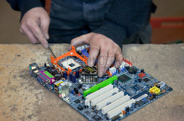 Berlin  Deutschland  Mitarbeiter der BRAL zerlegt eine PC-Hauptplatine in Einzelteile