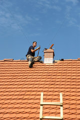 Sosnowka  Polen  Dachdecker legt letzte Hand an ein frisch gedecktes Dach