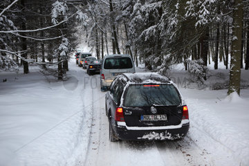 Neuenhagen  Deutschland  Autokolonne faehrt im Winter durch einen Wald