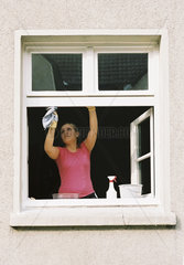 Junge Frau beim Fensterputzen