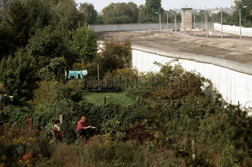 Rentnerpaar in ihrem Garten dirket an der Mauer in West-Berlin