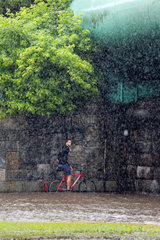 Warschau  Polen  ein Fahrradfahrer wartet auf das Ende eines starken Wolkenbruchs