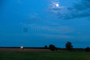 Neuhof  Deutschland  ein Traktor im Mondschein auf einem Feld