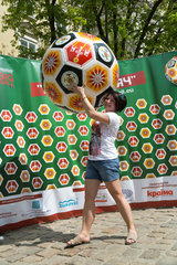 Lemberg  Ukraine  eine junge Frau laesst sich vor der Werbung fuer Amateur-Fussball fotografieren