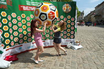 Lemberg  Ukraine  junge Frauen lassen sich vor der Werbung fuer Amateur-Fussball fotografieren