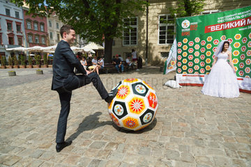 Lemberg  Ukraine  ein Brautpaar laesst sich vor der Werbung fuer Amateur-Fussball fotografieren