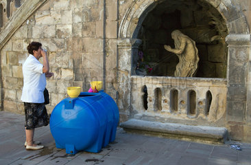 Lemberg  Ukraine  eine Frau trinkt geweihtes Wasser vor der St.-Georgs-Kathedrale