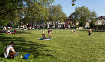 London  Grossbritannien  Menschen geniessen die Sonne auf einer Wiese im Stadtteil Hackney