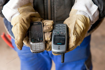 Berlin  Deutschland  Mitarbeiter der BRAL haelt alte Mobiltelefone in den Haenden