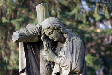 Berlin  Deutschland  trauernde Figur am Kreuz auf dem Friedhof am Suedstern