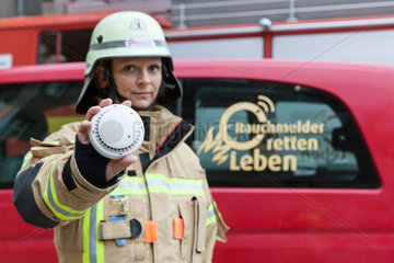 Berlin  Deutschland  Feuerwehrfrau zeig einen Brandmelder in die Kamera