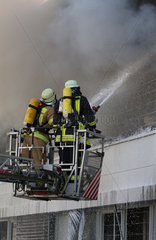 Berlin  Deutschland  Feuerwehrmaenner auf einer Drehleiter bei Loescharbeiten