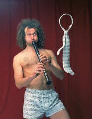 Berlin  Deutschland  Mann mit nacktem Oberkoerper laesst mit siener Floetenmusik eine Krawatte schweben
