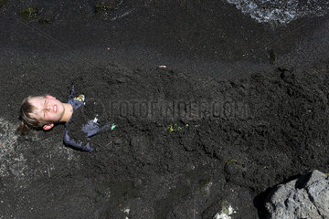 Bolsena  Italien  Junge ist in schwarzem Sand eingebuddelt