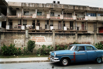 Santiago de Cuba  Kuba  blauer Oldtimer steht vor einem Mietshaus