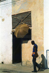 Santiago de Cuba  Kuba  Mann laeuft in der Mittagssonne an einem Hauseingang vorbei