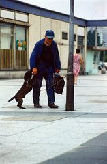 Berlin  DDR  Mann hat seinen Hund an einer Laterne angeleint
