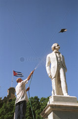 Havanna  Kuba  Mann verjagt mit einem Wasserstrahl einen Vogel vom Cespedes Denkmal