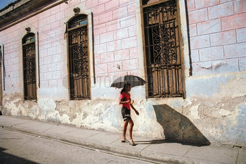 Santiago de Cuba  Kuba  Passantin mit Schirm in der Mittagssonne