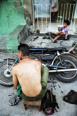 Havanna  Kuba  Mann bastelt an seinem Motorrad