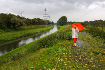 Oberhausen  Deutschland  eine junge Frau geht bei Regenwetter mit Regenschirm an der Emscher spazieren