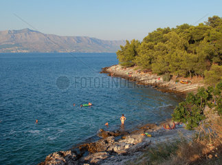 Postira  Kroatien  Insel Brac  Urlauber baden an einer Felsenkueste