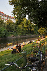 Berlin  Deutschland  junge Leute sitzen bei Sonnenuntergang am Ufer des Landwehrkanals am Maybachufer