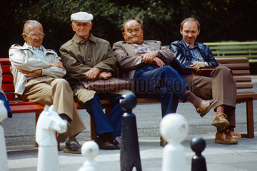 Berlin  DDR  Maenner sitzen auf einer Parkbank im Volkspark Friedrichshain