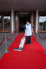 Freiburg  Deutschland  lateinamerikanische Putzfrau reinigt einen roten Teppich