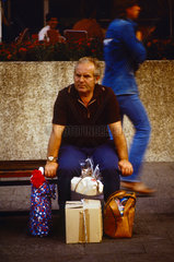 Berlin  DDR  Mann sitzt mit seinen Einkaeufen auf dem Alexanderplatz auf einer Bank
