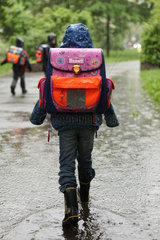Berlin  Deutschland  ein Kind laeuft auf dem Weg zur Schule durch eine Pfuetze