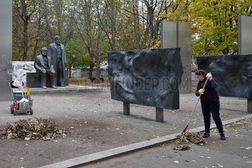 Berlin  Deutschland  Frau harkt Laub am provisorisch umgestellten Marx-Engels-Denkmal