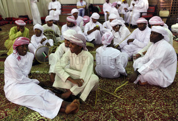 Dubai  Vereinigte Arabische Emirate  Maenner in Landestracht sitzen auf dem Boden