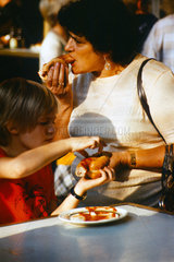 Berlin  DDR  Frau und Kind essen eine Currywurst beim Imbiss Konnopke
