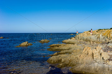 Capo Comino  Italien  Angler an der Felsenkueste von Capo Comino auf der Insel Sardinien