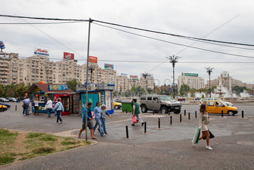 Bukarest  Rumaenien  Passanten und Wohnhaeuser mit Werbetafeln am Platz der Einheit