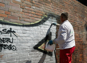 Berlin  Deutschland  Entfernung von Graffiti an einer Backsteinmauer