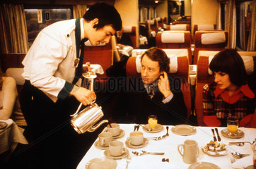 Steward serving coffee to a couple on the train  1975-1985.
