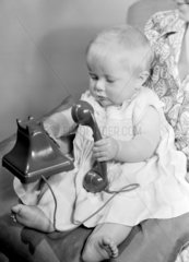 Baby playing with a telephone  1950.