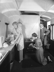 Holidaymakers preparing food inside a camping coach  1936.