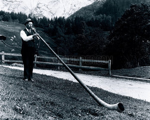 Alpine musician blowing his horn  c 1920s.