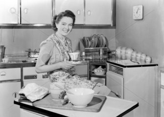 Woman drinking tea in a kitchen  1950.