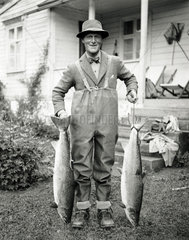 Angler holding up a pair of salmon  Eastern Seaboard  USA  c 1930s.
