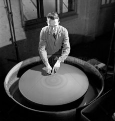 An operator polishes a lens on large rotary disc  Taylor-Hobson  1953.