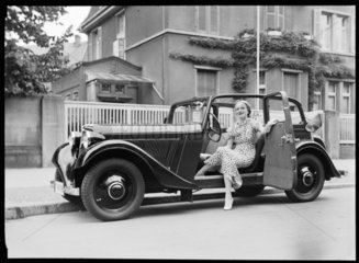 A woman sits in the door of an Adler motor car  c 1934.